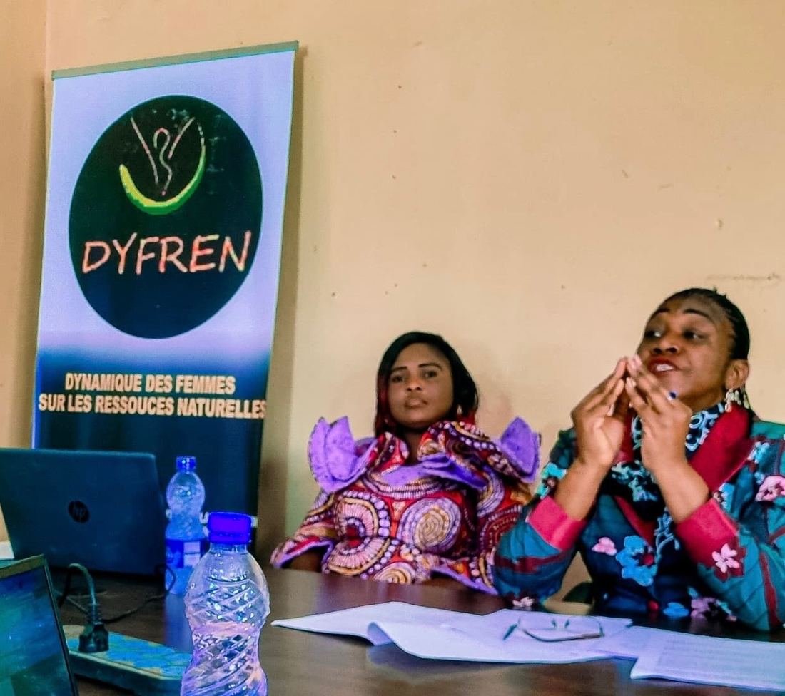 Two DYFREN women at a working session next to the organisation's banner
