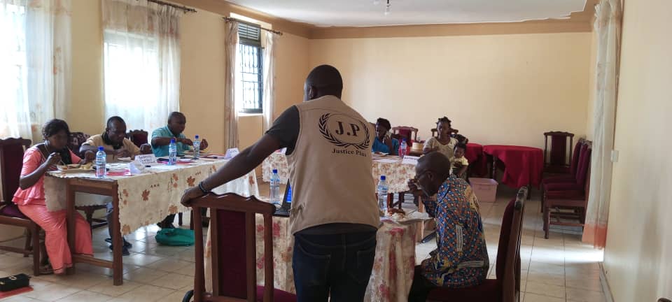 A Justice Plus facilitator in a branded vest leads a community paralegal training session