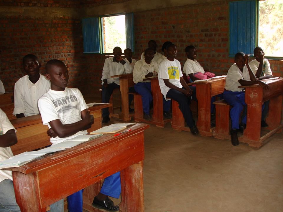 Students at wooden desks inside a rural classroom supported by Strong Roots community programmes